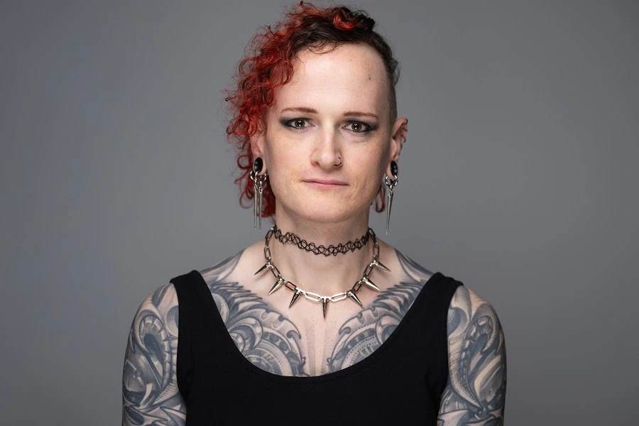 woman in black sleeveless dress with red colored hair against grey background